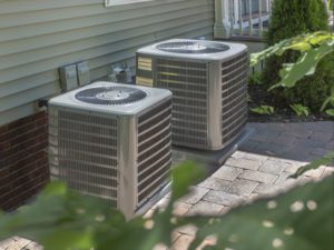 Two outdoor HVAC units next to a home.